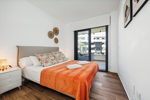 Ein Schlafzimmer mit Bett, Nachttisch und Blick durch eine Glastür.