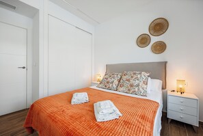 A hotel room with a bed, two bedside tables, a wardrobe, and decorative wall art. - Charming 2-bedroom apartment with AC in tranquil Villamartín (Villamartín)