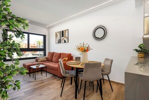 A modern living room with a sofa, coffee table, and dining area with chairs. There are wall art pieces and a decorative mirror. - Charming 2-bedroom apartment with AC in tranquil Villamartín (Villamartín)