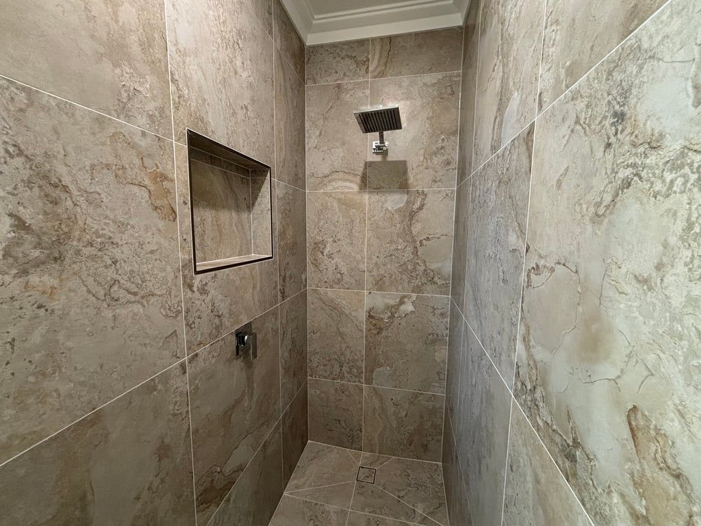 A bathroom with a shower, tiled walls, and a mirror.