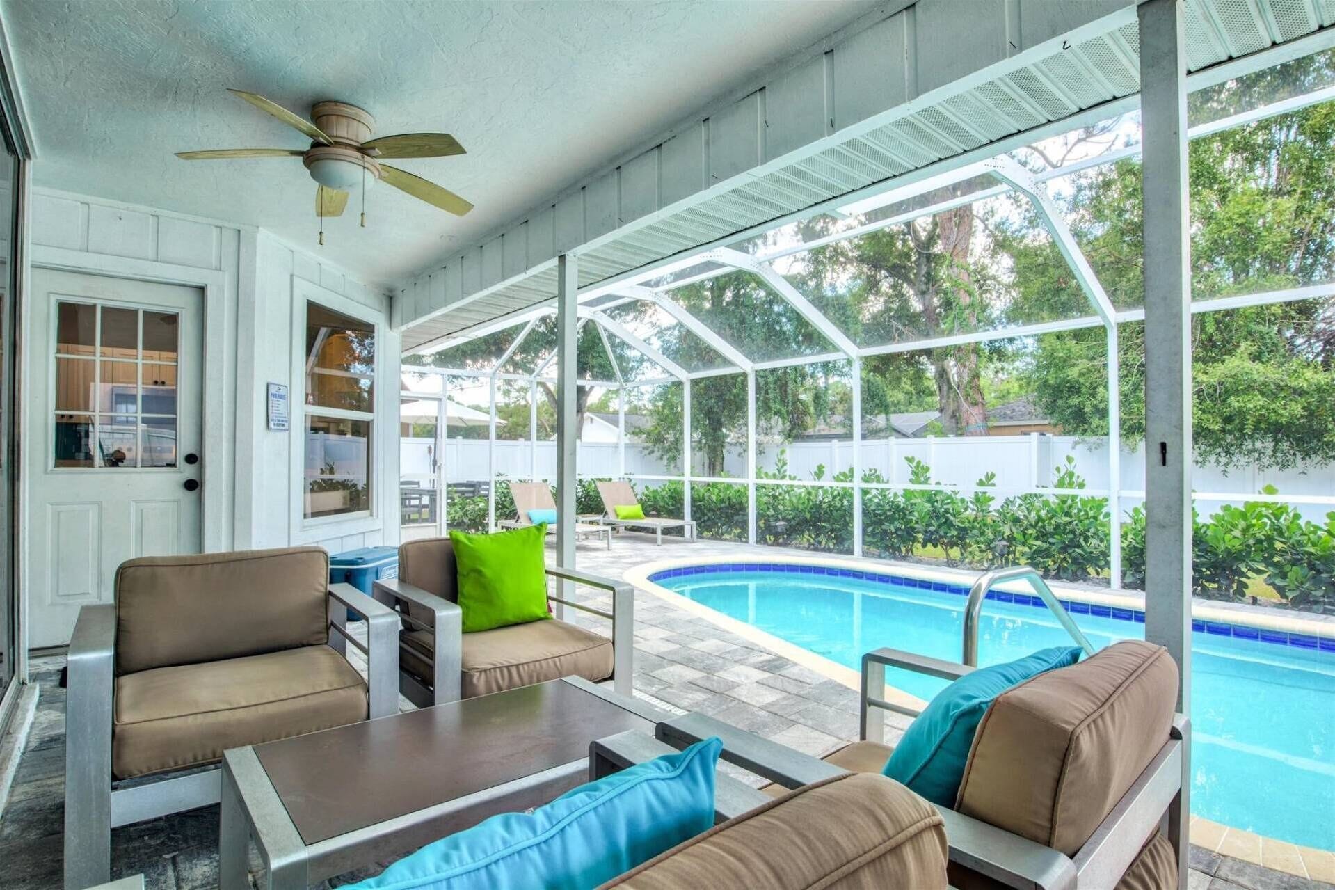 A covered outdoor area with a pool, seating, and a ceiling fan.