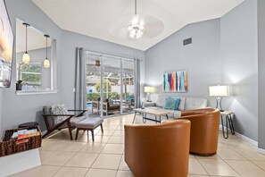 A modern living room with a sofa, two armchairs, a coffee table, and a dining area with a basket. - Vacation Rental Near Downtown Sarasota & Area Beaches with Private Pool (Sarasota)