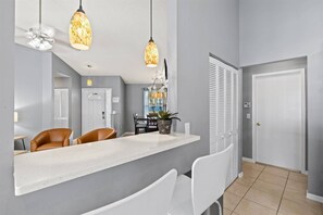 A modern kitchen with a white countertop, two pendant lights, and a dining area with chairs. - Vacation Rental Near Downtown Sarasota & Area Beaches with Private Pool (Sarasota)