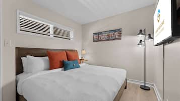 Hotelkamer met een bed, een televisie, een kunstwerk aan de muur en een vloerlamp.