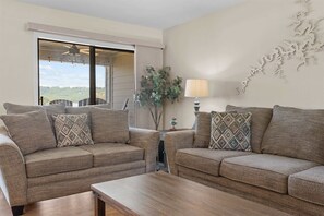 A living room with two sofas, a coffee table, a lamp, and a view through a large window. - Treasured Lake Views - 2 Patios (Kimberling City)
