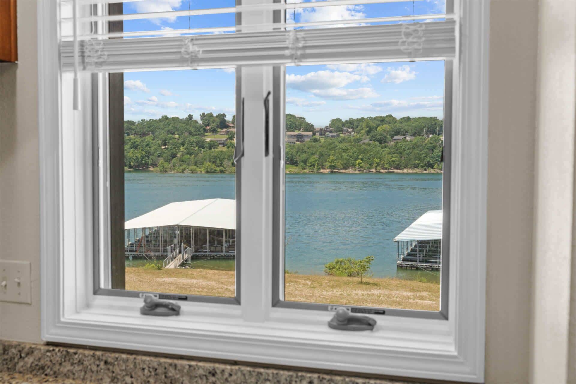 A window with a view of a lake and a white structure on the shore.