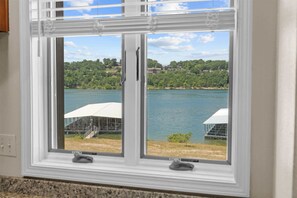 A window with a view of a lake and a white structure on the shore. - Treasured Lake Views - 2 Patios (Kimberling City)