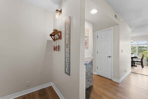 A hallway with a wooden coat rack, a wall-mounted sign reading 'LAKE HOUSE,' and a white door leading to a room with a view. - Treasured Lake Views - 2 Patios (Kimberling City)