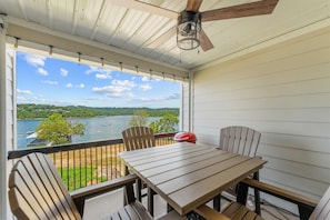 A covered outdoor area with a table and chairs, a ceiling fan, and a view of a lake. - Treasured Lake Views - 2 Patios (Kimberling City)