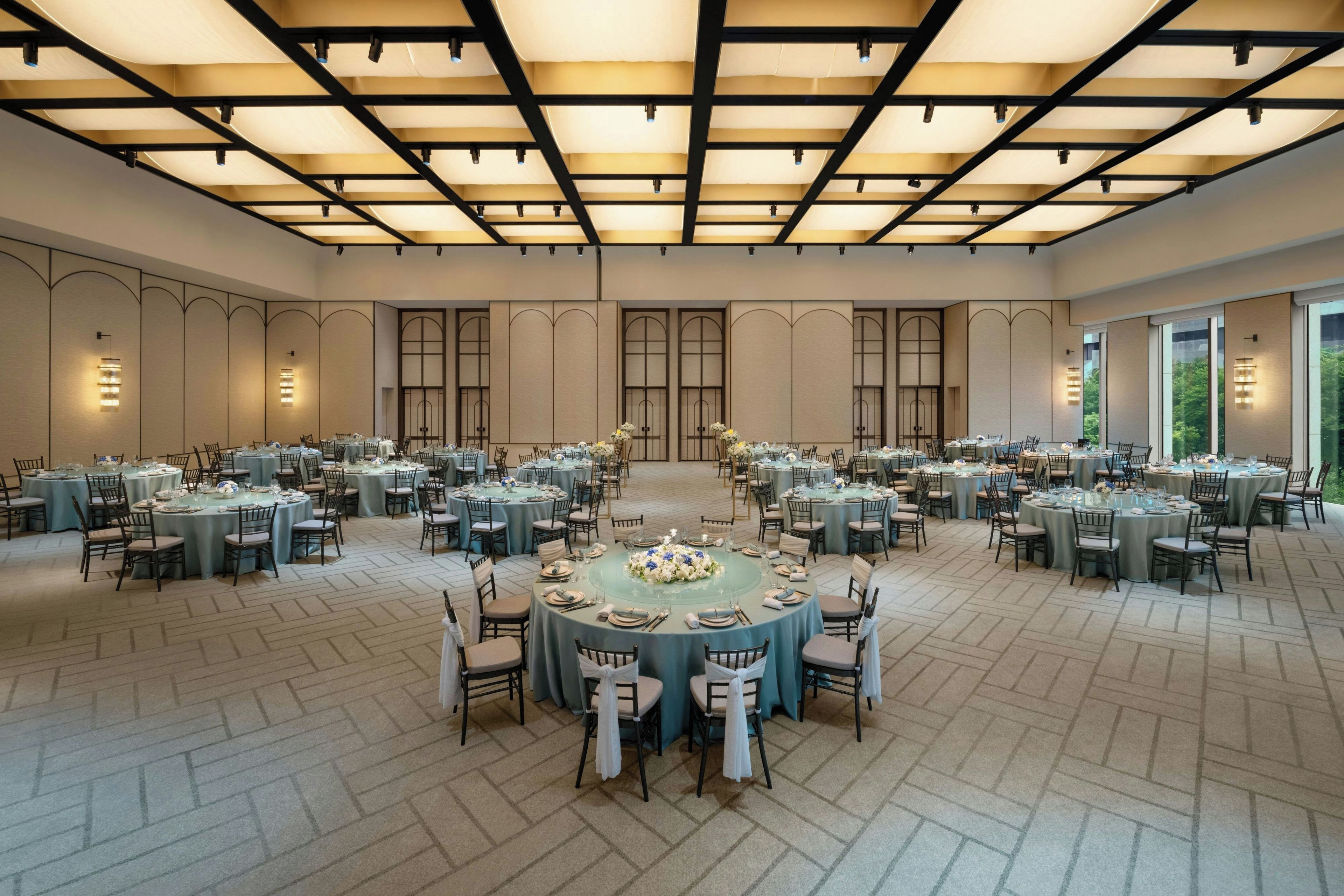 A large banquet hall with multiple round tables, each set with chairs and table settings.