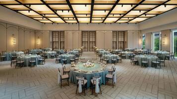 A large banquet hall with multiple round tables, each set with chairs and table settings.