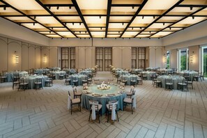 A large banquet hall with multiple round tables, each set with chairs and table settings.