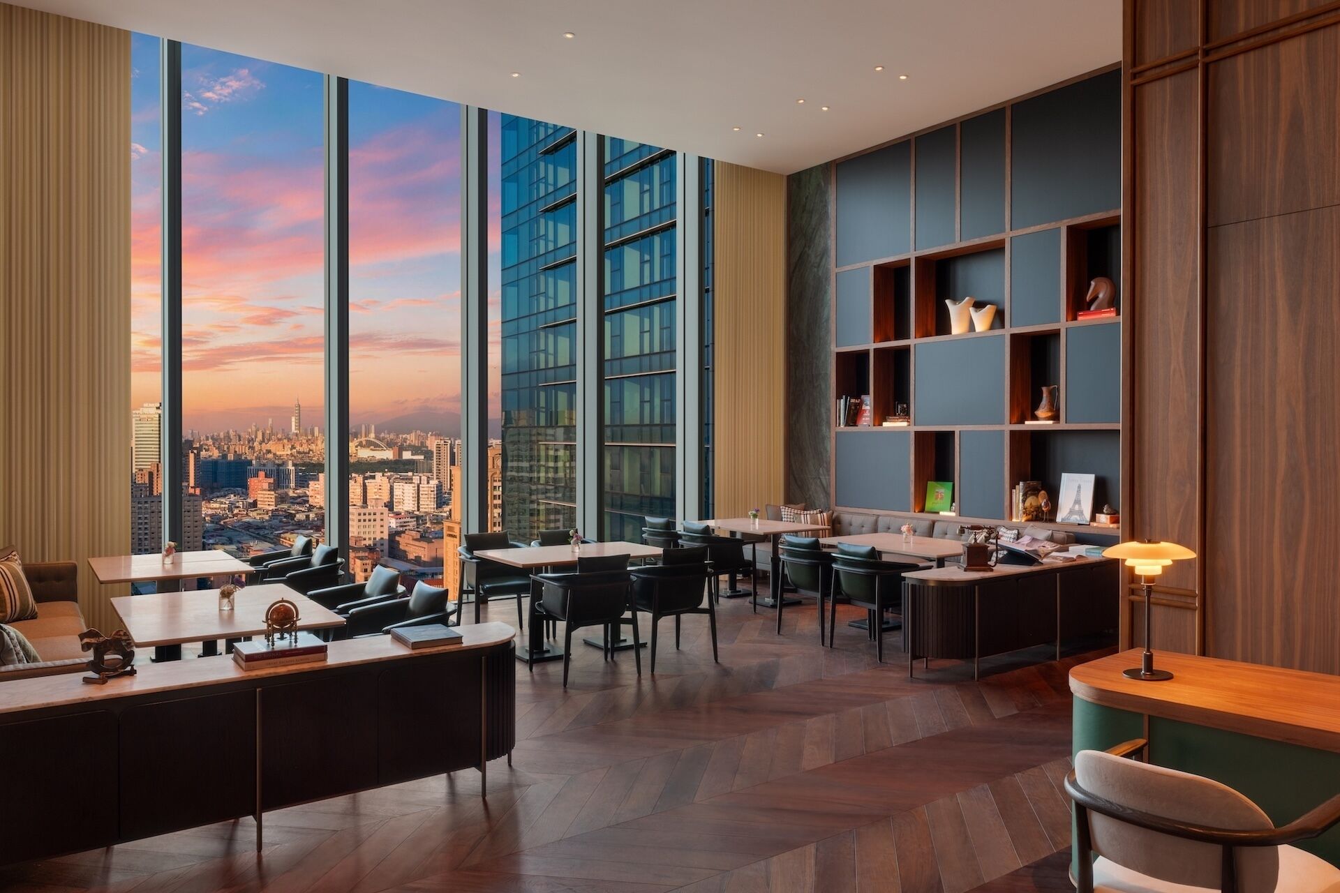 A modern interior with a panoramic city view, a bar area, and a seating section with a fireplace.