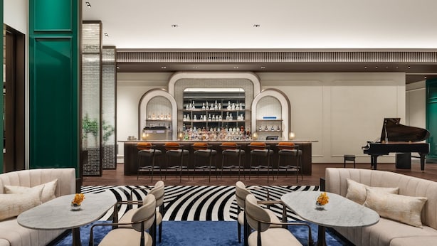 Een bar met een piano, barstoelen en een zithoek met banken en tafels.