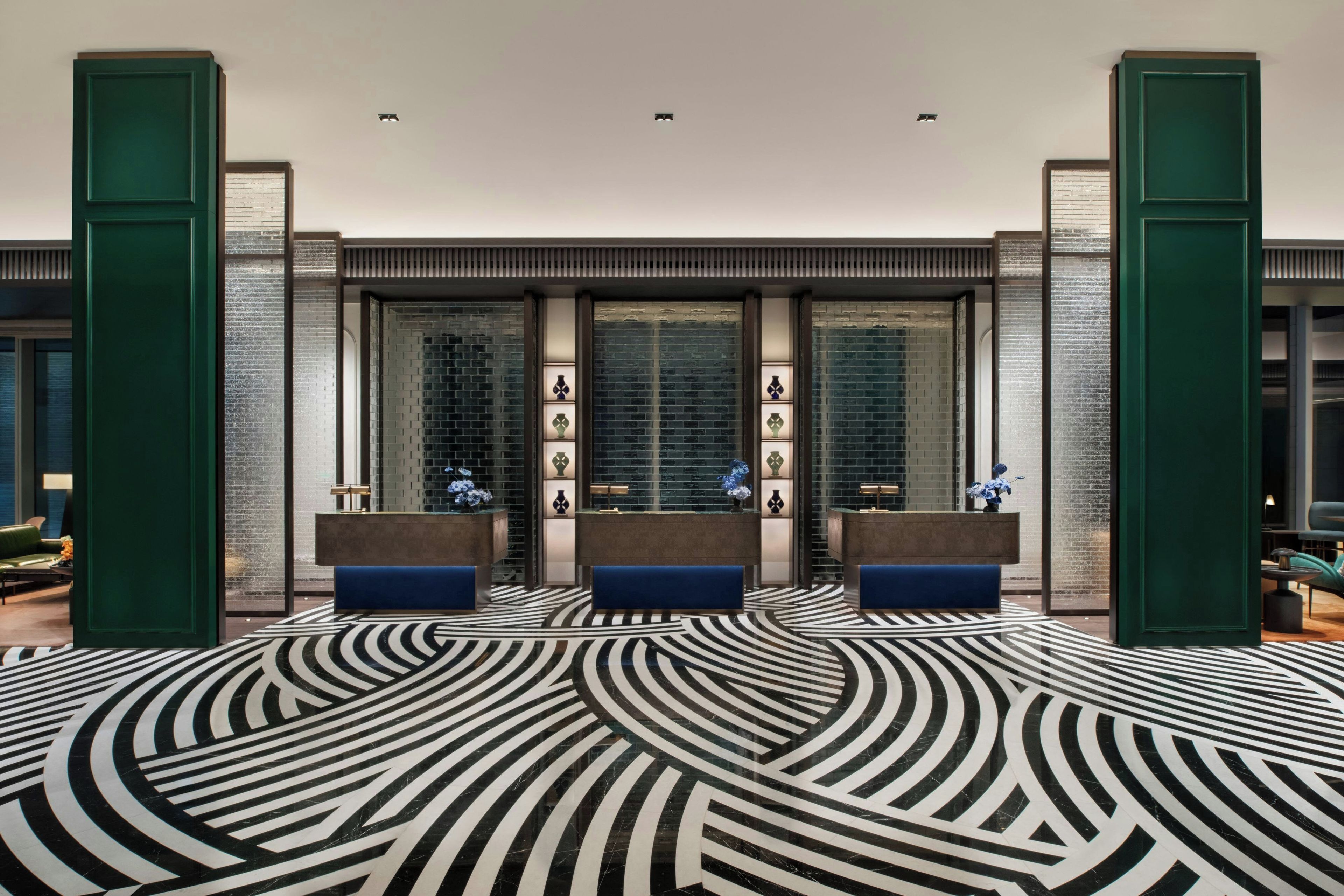 A lobby with a patterned floor, reception desks, and a brick wall.