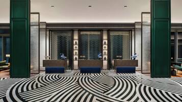 A lobby with a patterned floor, reception desks, and a brick wall.
