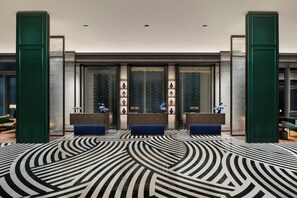A lobby with a patterned floor, reception desks, and a brick wall.