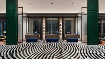 A lobby with a patterned floor, two reception desks, and a glass partition with decorative items.