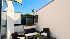 En terrasse med udendørs møbler, et fjernsyn og en grill.