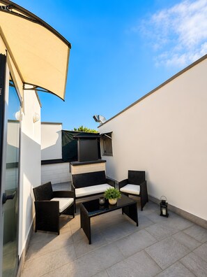 Eine Terrasse mit Gartenmöbeln, einem Fernseher und einem Grill.