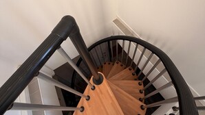 En spiralformet trappe med trætrin og metalgelændere.