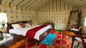 A room with a bed, a chair, a table, and a patterned wall.
