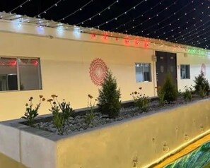 A building facade with a series of windows and a decorative circular pattern on the wall. - Kumbh India Kutir (Trimbak)