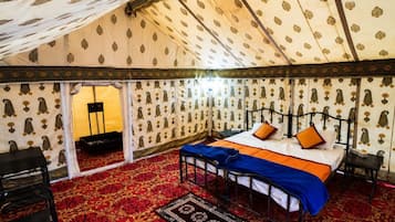 A tent-style room with a bed, a chair, and a small table.