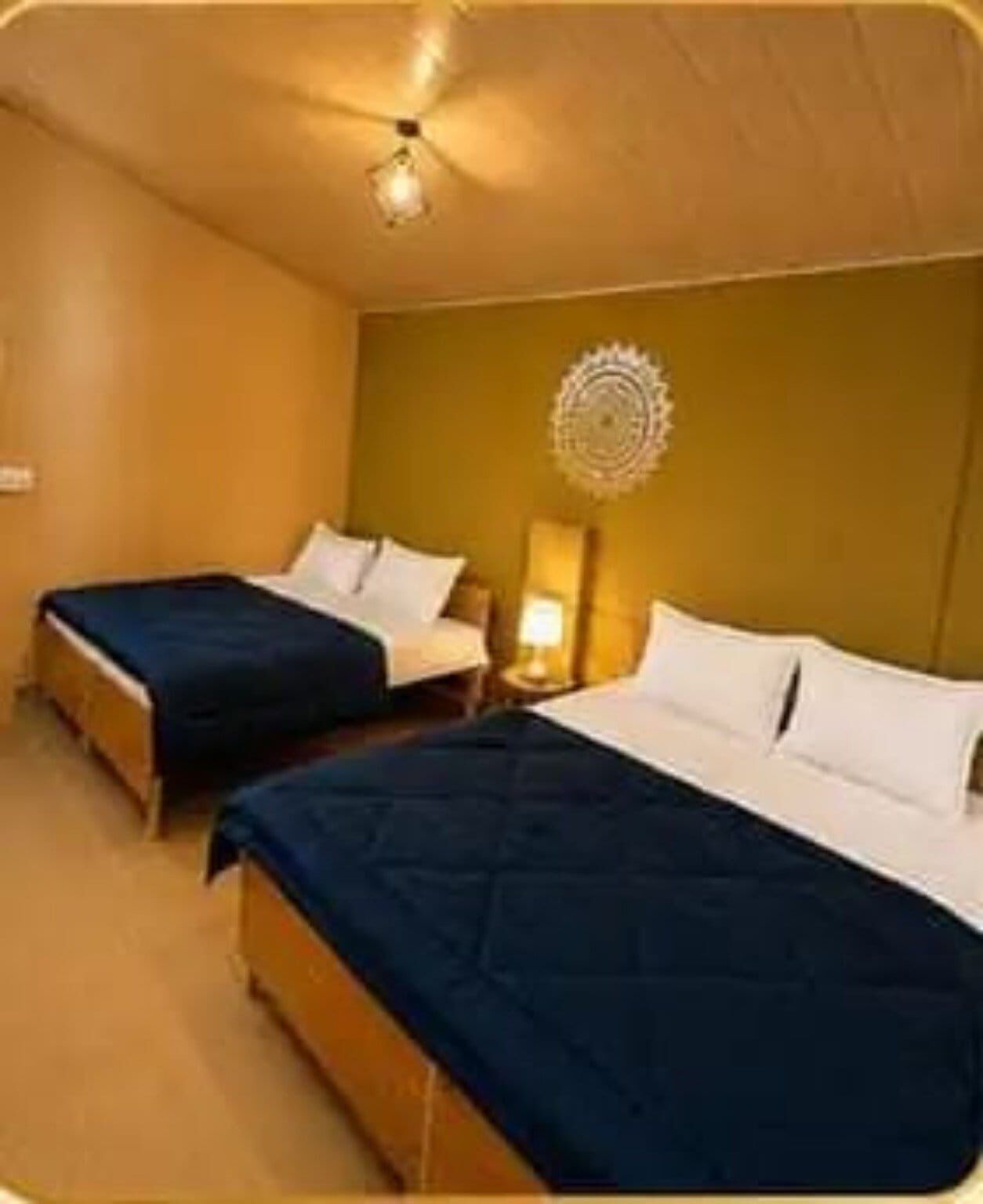 A hotel room with two single beds, a ceiling fan, and a wall-mounted decorative item.
