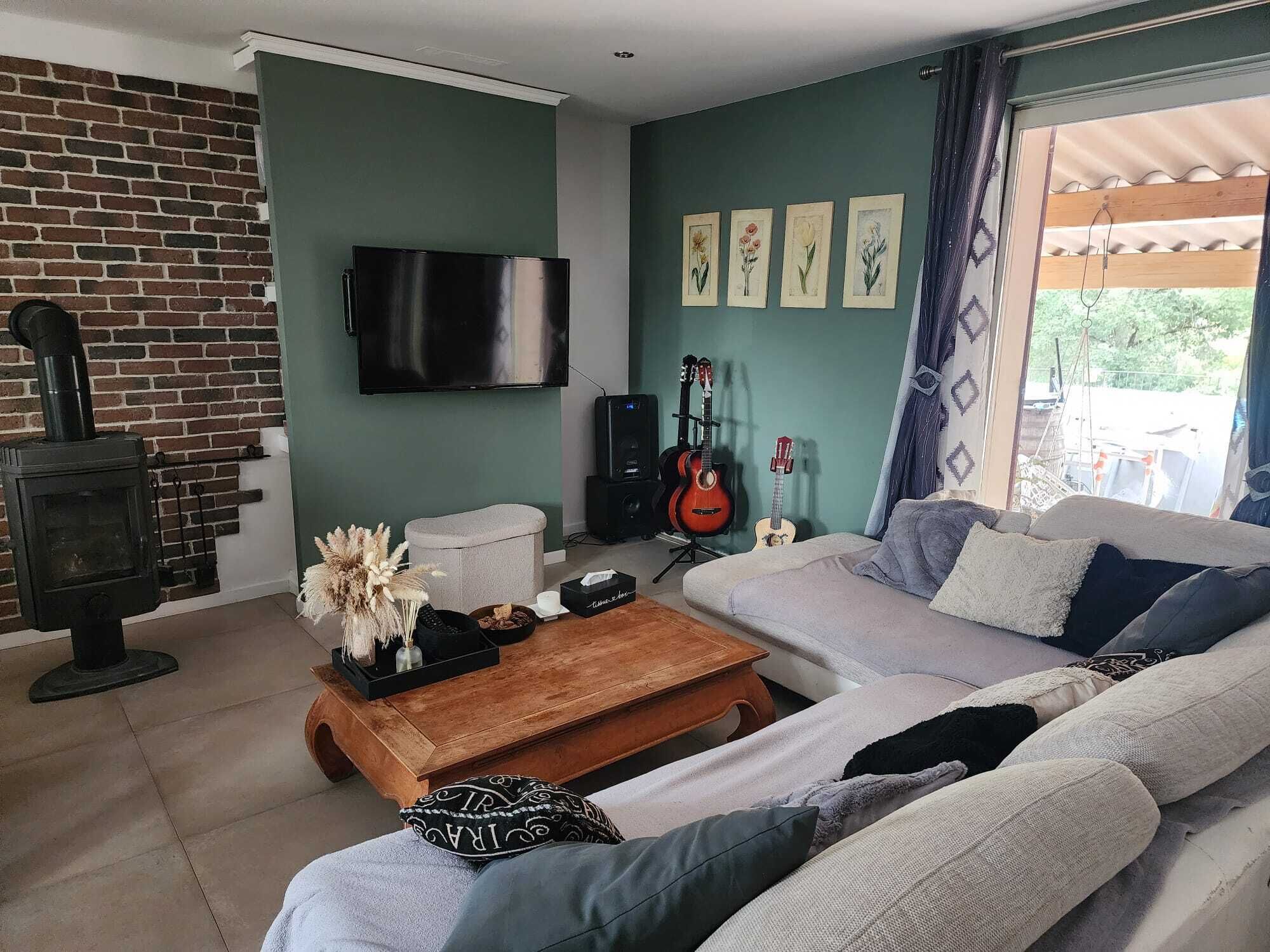 Una sala de estar con pared de ladrillo, chimenea, sofá, mesa de centro y televisor montado en la pared.