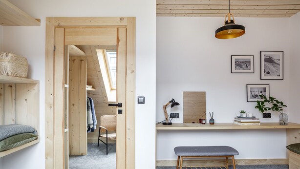 Una habitación con cama alta, escritorio con lámpara y lámpara colgante.