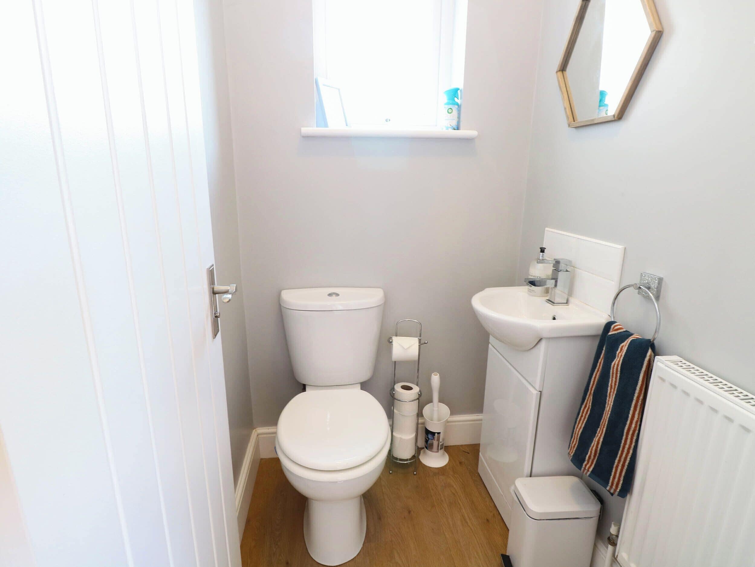 A compact bathroom with a toilet, sink, and a window above the toilet.