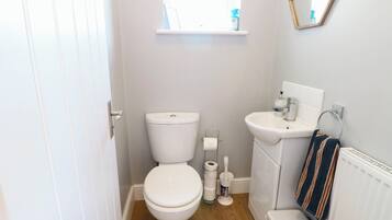 A compact bathroom with a toilet, sink, and a window above the toilet.