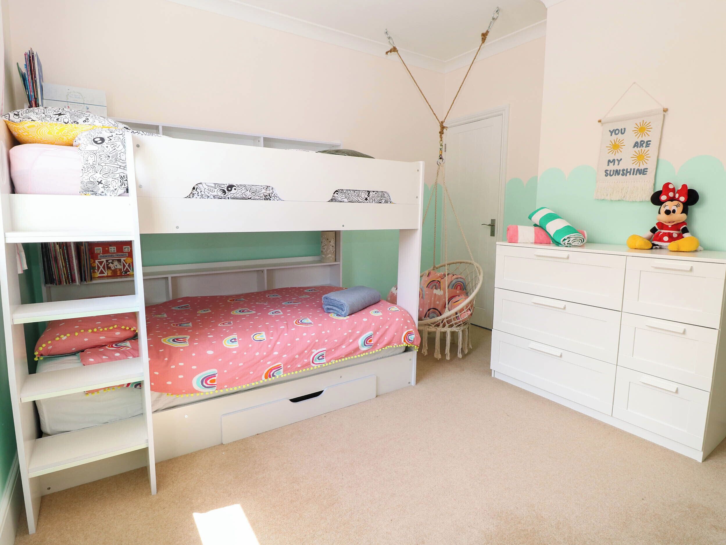 A bunk bed room with a hanging chair, a Minnie Mouse plush toy, and a motivational wall sign.