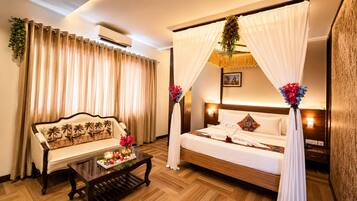 A hotel room with a bed, a sofa, a coffee table, and curtains.