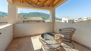 A balcony with a view of a village, a table, and two wicker chairs. - Holiday Home 'Ca La Mala' with Shared Terrace, Balcony and Wi-Fi (Biar)
