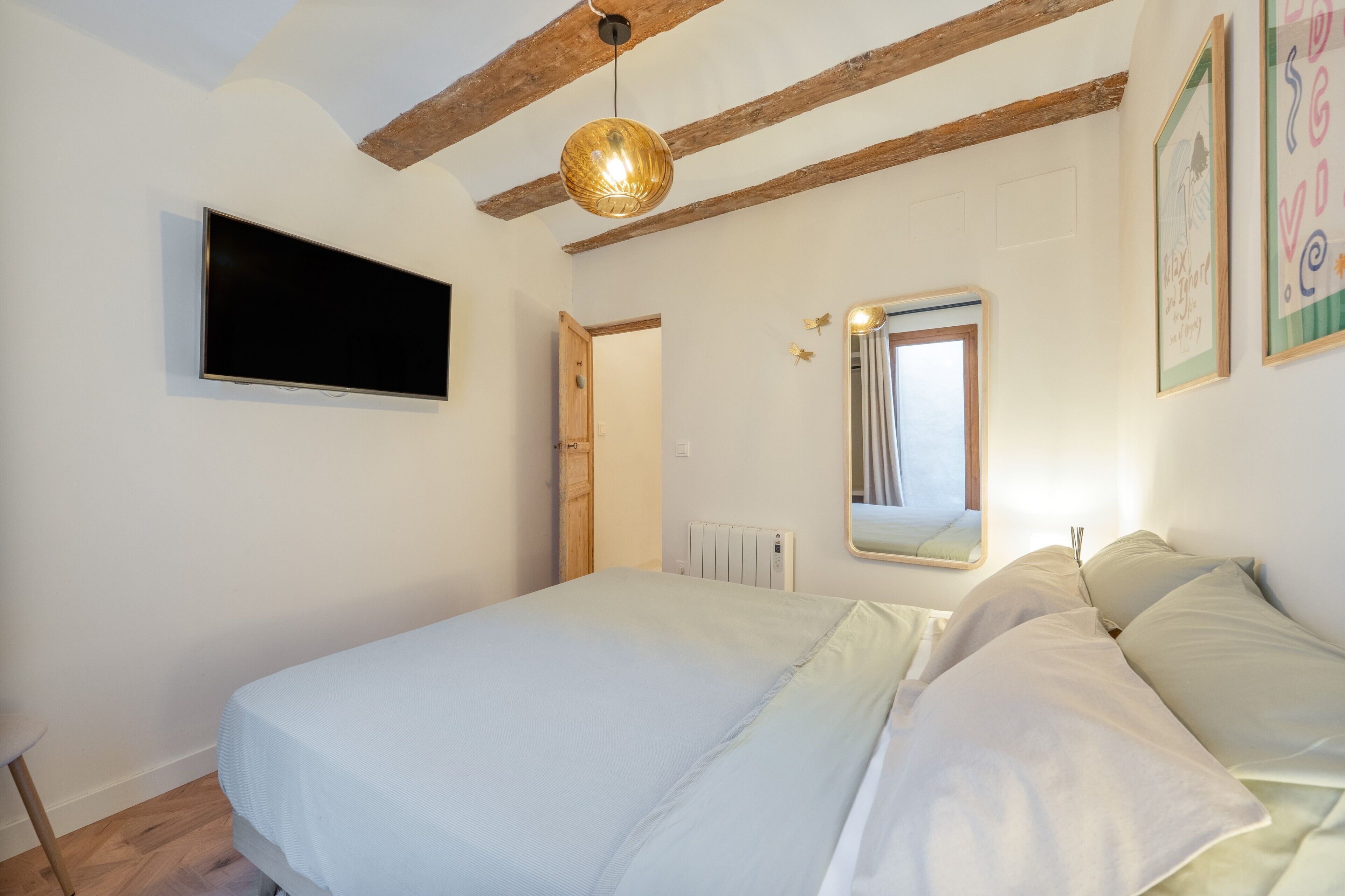 Un dormitorio con cama, televisión, radiador y puerta.