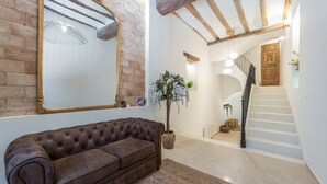 A room with a brown leather sofa, a large mirror, a potted plant, and a staircase leading to another level. - Holiday Home 'Ca La Mala' with Shared Terrace, Balcony and Wi-Fi (Biar)