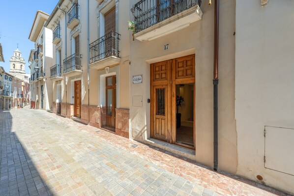 A street with buildings, a tiled pavement, and a sign with the number 17.