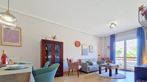 Olohuone, jossa on ruokailutila, sohva, kaappi ja näkymä lasiovesta.