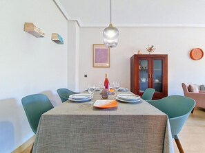 A dining area with a table set for four, a wine bottle, and a framed picture on the wall. - South-West Facing Balcony with Pool Views (Los Alcazares)