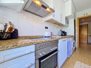 A modern kitchen with white cabinets, a granite countertop, a built-in oven, and a microwave. - South-West Facing Balcony with Pool Views (Los Alcazares)