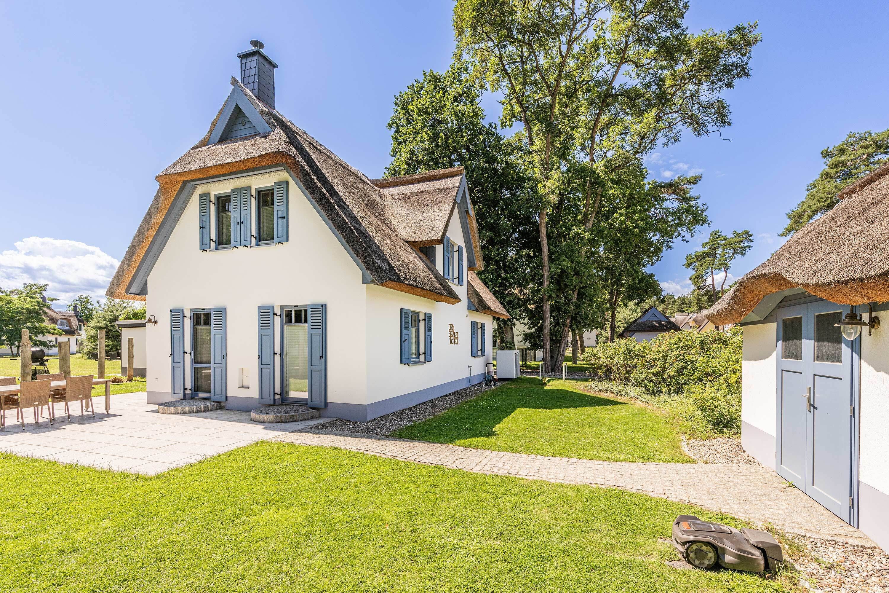 A two-story house with a thatched roof, a paved patio, and a lawn.