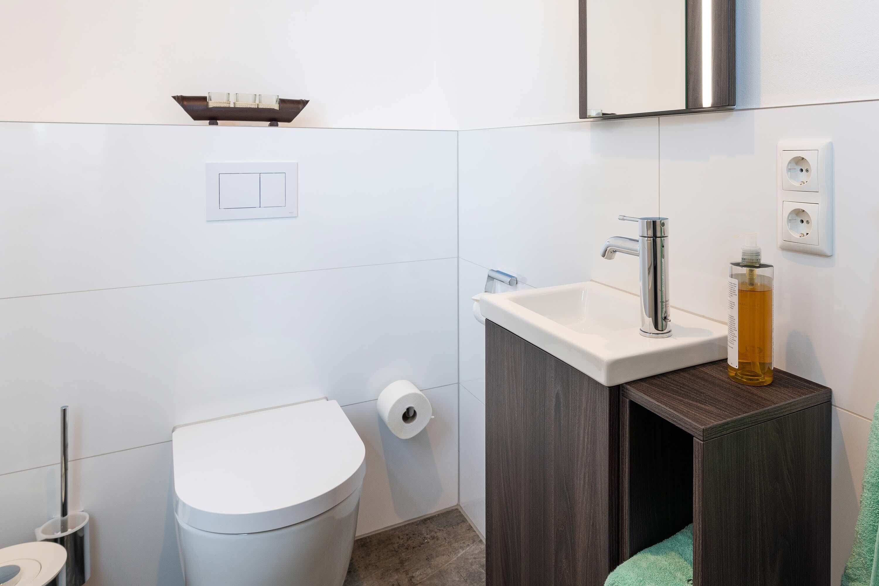 A modern bathroom with a toilet, sink, and mirror.