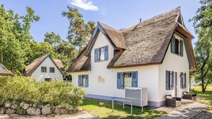 Um edifício em estilo chalé tradicional, com telhado inclinado, várias janelas com persianas e um jardim bem cuidado.