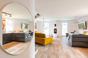 A modern kitchen with a central island, a dining area with a yellow sofa, and a fireplace. - Modern vacation home in Zirchow for a relaxing getaway in an idyllic forest setting (Zirchow)