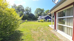Et hus med stor glasdør, hegnet gårdhave og solpanel på taget.