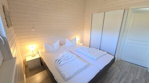 Ein Schlafzimmer mit Bett, Nachttischlampen, einem Nachttisch und einem Kleiderschrank.
