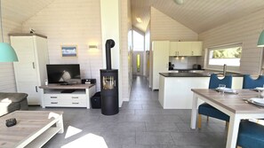 Ein modernes Blockhaushaus-Interieur mit Fernseher, Kamin, Essbereich und Küche.