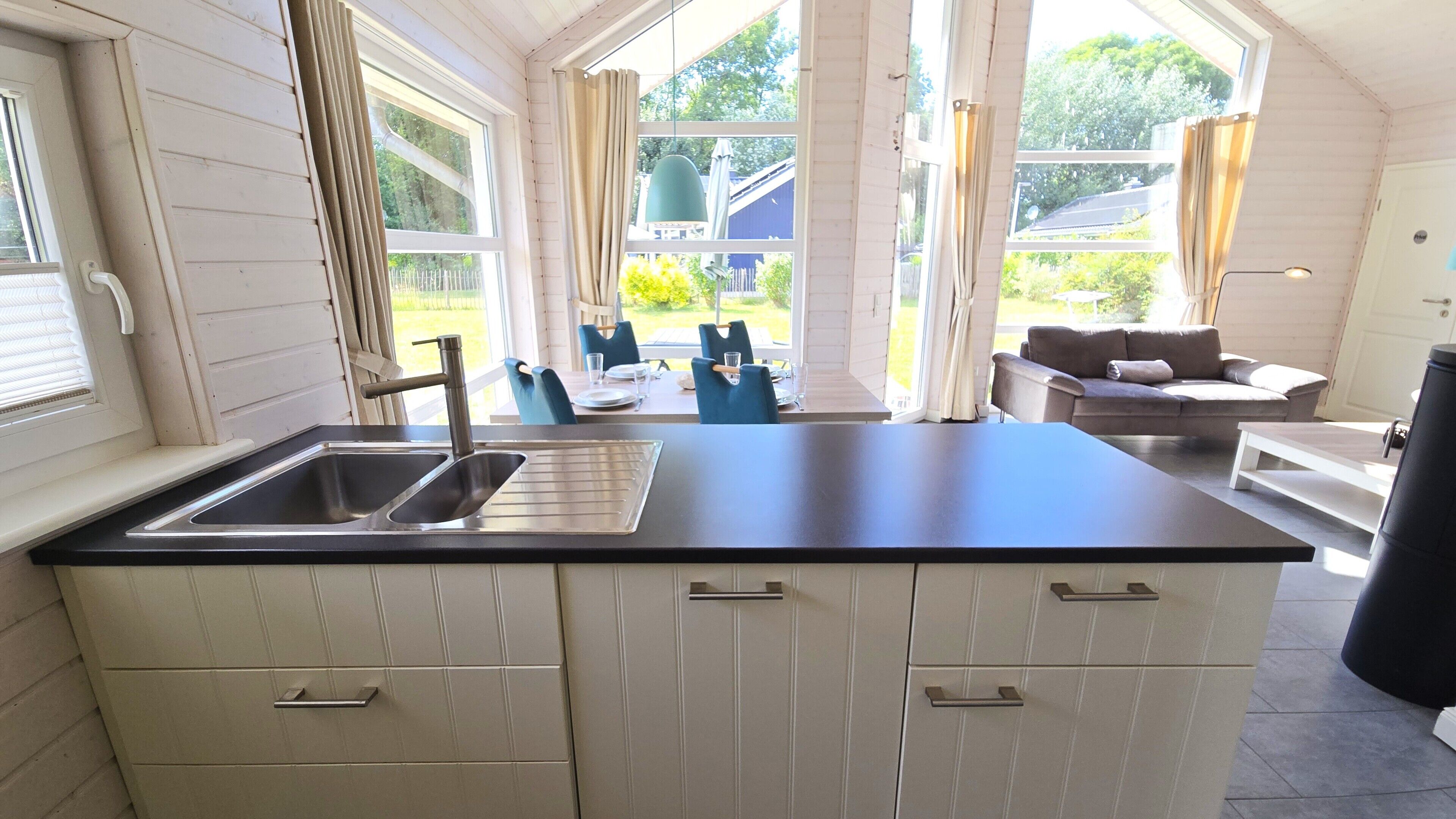 Una cocina con una isla grande, un lavamanos y una zona de comedor con sillas y una mesa.